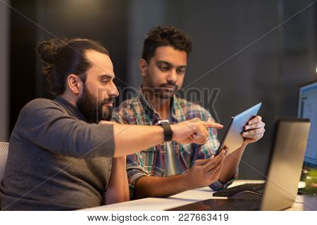 deadline, technology and people concept - creative team with tablet pc computer working together late at night office