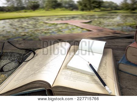 Old Books With Treatise, Glasses And Pencil On A Wooden Table In The Garden. Concept Education.