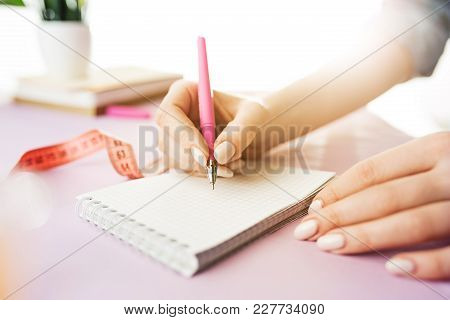 The Female Hands Holding Pen. The Trendy Pink Desk.