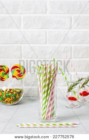 Glass With Striped Green And Pink Drinking Straws And Colored Candies And Lolipops In A Glass Round 