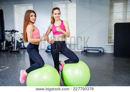 Two Smiling Girls Showing Thumbs Up In Gym