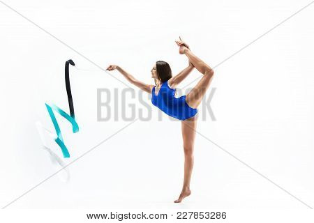 The Portrait Of Beautiful Young Brunette Woman Gymnast Training Calilisthenics Exercise With Blue Ri