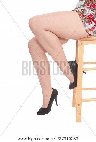 A Close Up Image Of The Legs Of A Young Woman In A Dress Sitting On
A Barchair In Black Heels, Isola