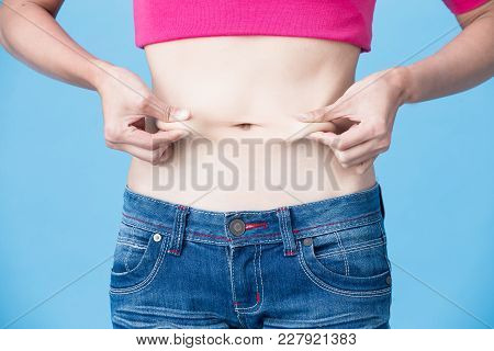 Woman Pinch Her Belly On The Blue Background