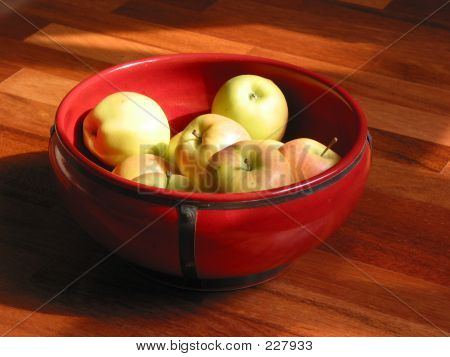 Manzanas amarillas en un recipiente rojo