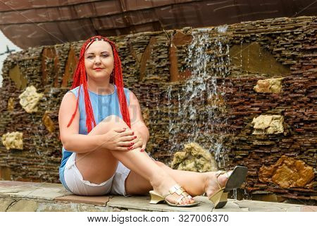 Young Woman With Red Hair On A Background Of Fountain Jets.
