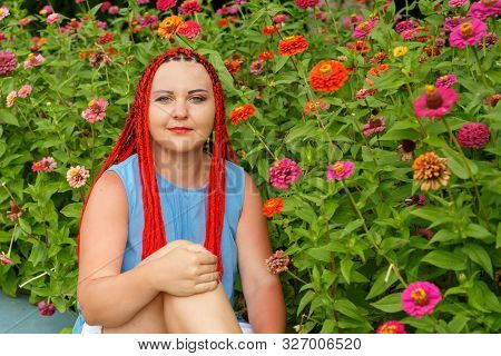 Closeup Of A Young Woman With Red Hair Among Red Orange Flowers.