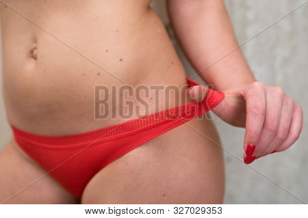 Elegant Female Hand With A Red Manicure Pulls Aside The Elastic Of The Panties On The Thigh. Lingeri