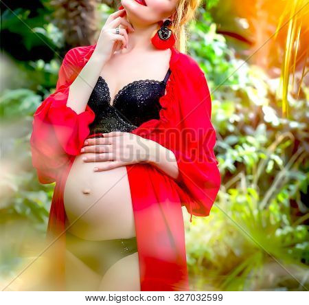 Pregnant Blonde Girl In A Red Tunic And With Earrings In The Tropics Walks