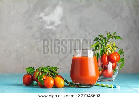Glass Of Fresh Delicious Jummy Red Tomato Juice And Fresh Tomatoes On Light Concrete Surface. Close