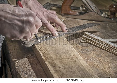 Carpenter Marking Measurements On Piece Of Wooden Board