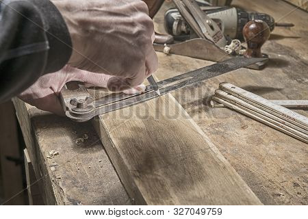 Carpenter Marking Measurements On Piece Of Wooden Board