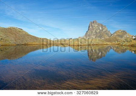 Midi Dossau Peak reflected in a lake. Ossau Valley, Pyrenees National Park, Pyrenees, France.