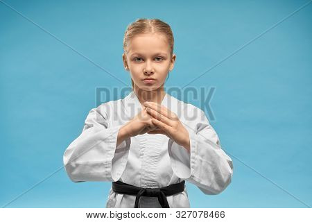 Young Concentrated Karate Girl Practicing Hands Position. Pretty Junior In White Kimono With Black B