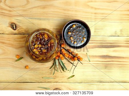 Jar Of Sea Buckthorn Jam, A Bowl With Sea Buckthorn Jam And A Branch Of Sea Buckthorn On A Wooden Ta
