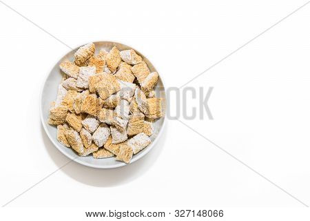 A Full Bowl Of Whole Grain Frosted Cereal Placed Off Center On A White Background.  The Shadows From