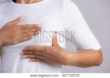 Woman Hand Checking Lumps On Her Breast For Signs Of Breast Cancer On Gray Background. Healthcare Co