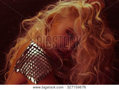 beautiful woman with silver scales on the man as a dragon armor, with the hair in the wind in sensual poses on rustic gray background