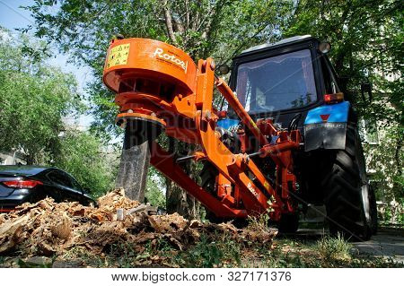 Tractor With A Special Nozzle For Crushing And Rooting Out Stumps Works On A City Street. Urban Econ