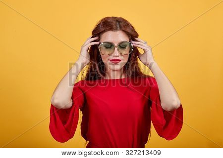 Beautiful Girl With Closed Eyes Wearing Brown Sunglasses. Cute Lady In Red Garment Holding Glasses P