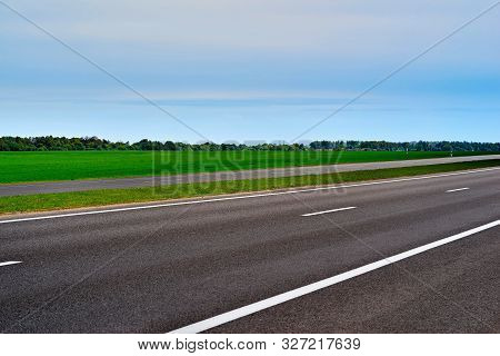 Asphalt Road Or Highway Closeup Against The Background Of Rural Landscape With Green Sown Field And 