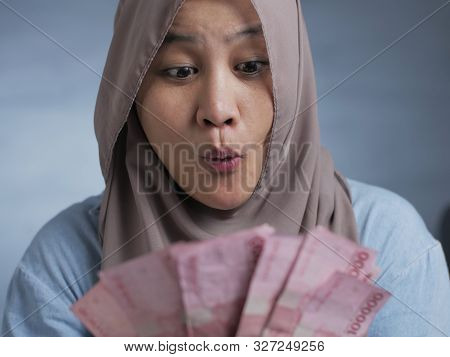 Portrait Of Indonesian Muslim Woman Receiving Rupiah Money, Smiling Joyful Gesture
