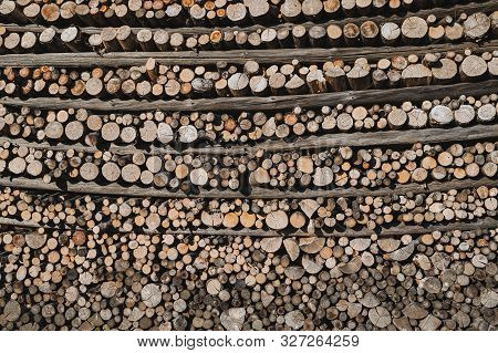 In Precise Order Folded Firewood In Between Horizontal Crossbars Of A Hayrack.