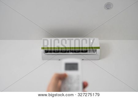 Mans Hand Using Remote Controler. Hand Holding Rc And Adjusting Temperature Of Air Conditioner Mount