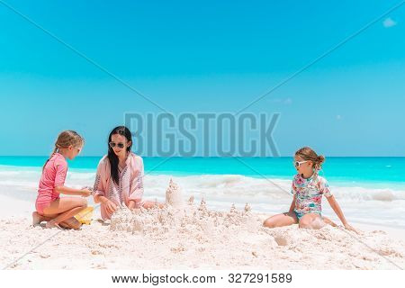 Family Making Sand Castle At Tropical White Beach. Mother And Two Girls Playing With Sand On Tropica