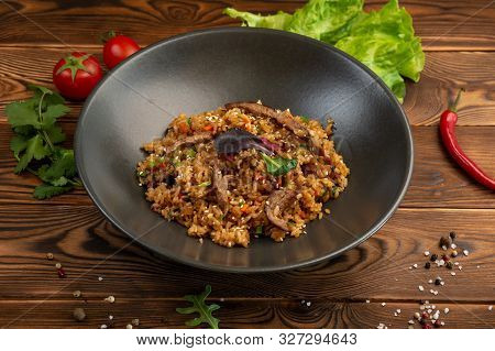 Beef Chahan Fried Japanese Rice With Vegetables And Slices Of Beef In A Black Plate On A Wooden Back