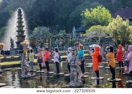 Bali, Indonesia - 17 September 2019: People praying on the stepstones of Tirtagangga Water Palace in Bali, Indonesia