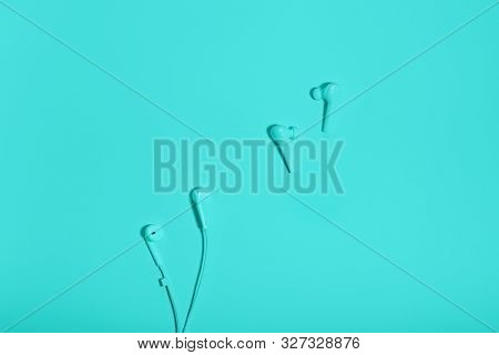 Wireless In Ear Headphones And Cable Earphones On Blue Background Close Up. Minimal Music Concept. W
