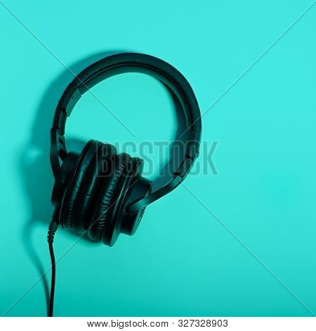 Black Over Ear Headphones Closeup On Blue Background, Top View. Minimal Music Background, Copy Space