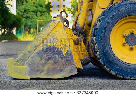 Bucket And Wheels Of Heavy Construction Equipment. Side View. Yellow Metal Bucket With Scratches. Di