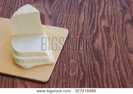 Adyghe Cheese On A Cutting Board. Brown Wood Background. Sliced