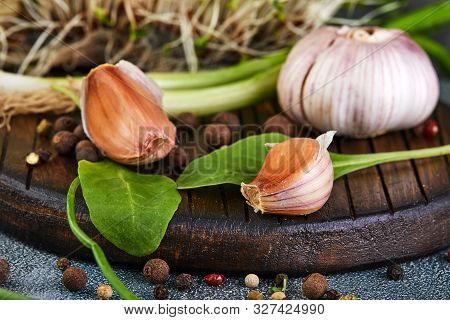 Garlic, Chives, Rudiments And Peas Of Pepper On A Wooden Background.