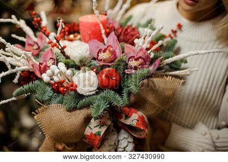 Woman Holding A Christmas Composition With Pink Orchids, White Roses, Fir-tree Branches, Red Apple A