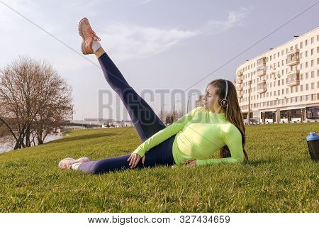 1 White Girl With Long Hair In Sportswear , Sneakers Doing Fitness, Lifting Her Legs In The Air