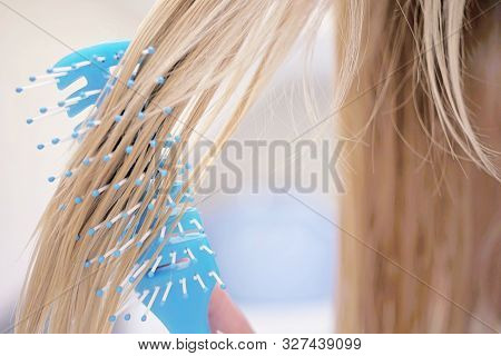Blue Comb Combs Wet Blond Hair, Close-up.