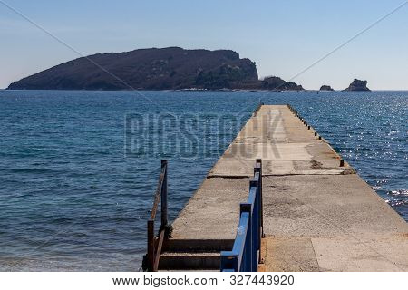 Empty Pier On Beach Greco With A View Of Saint Nikola Island In The Background In Budva, Montenegro
