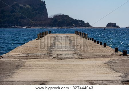 Empty Pier On Beach Greco With A View Of Saint Nikola Island In The Background In Budva, Montenegro