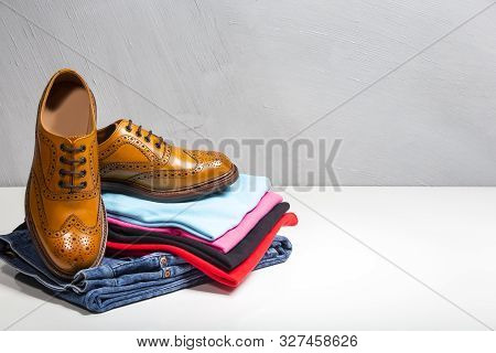Pair Of Male Full Brogued Tan Oxford Shoes Placed On Top Of Heap Of Clothing. Horizontal Image