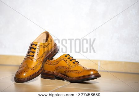 Pair Of Male Full Brogued Tan Oxford Shoes. Placed Together On Tiles Floor. Horizontal Image