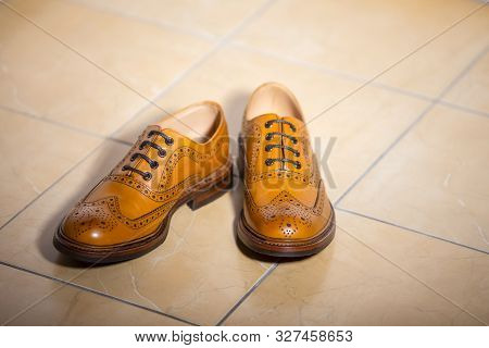 Pair Of Male Full Brogued Tan Oxford Shoes. Placed Together On Tiles Floor. Horizontal Image Composi