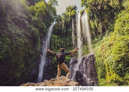Man In Turquoise Dress At The Sekumpul Waterfalls In Jungles On Bali Island, Indonesia. Bali Travel 