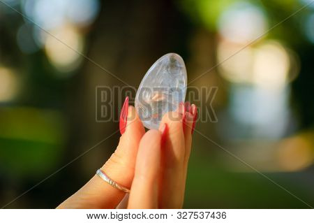 Female Hand With Transparent Amethyst Quartz Yoni Egg For Vumfit, Imbuilding Or Meditation. Shining 