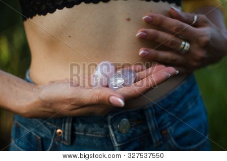 Female Hands Holding Two Yoni Eggs For Vumfit, Imbuilding Or Meditation Are Made From Pink Quartz An