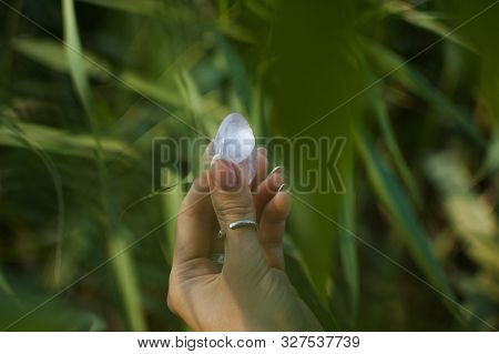 Female Hand With French Manicure Holding Transparent Violet Amethyst Yoni Egg For Vumfit, Imbuilding
