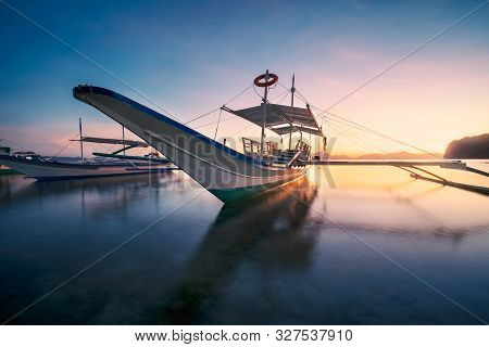 El Nido, Palawan, Philippines. Traditional Banca Boat In The Beach Bay In Golden Sunset Light. Tranq