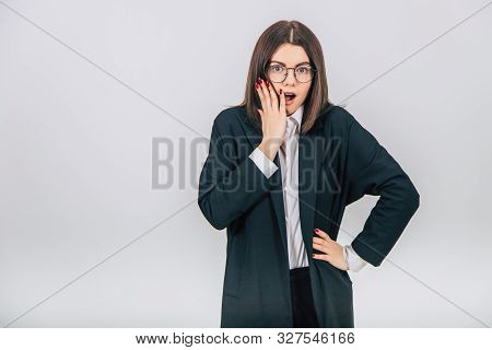 Lovely Young Businesswoman In Black Suit Standing, Covering Her Mouth, Surprised By Somrthing, Hand 